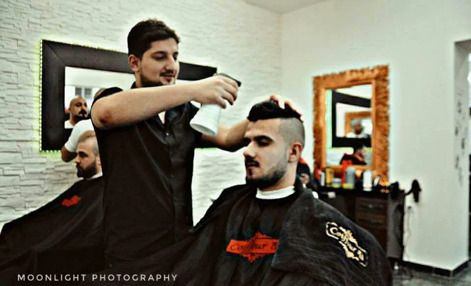 Ein Coiffeur stylt einem Kunden die Haare, im Hintergrund ein Spiegel
